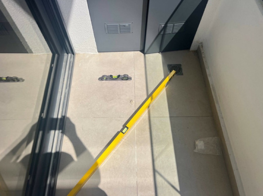 Spirit level on a veranda floor showing no fall towards the drain