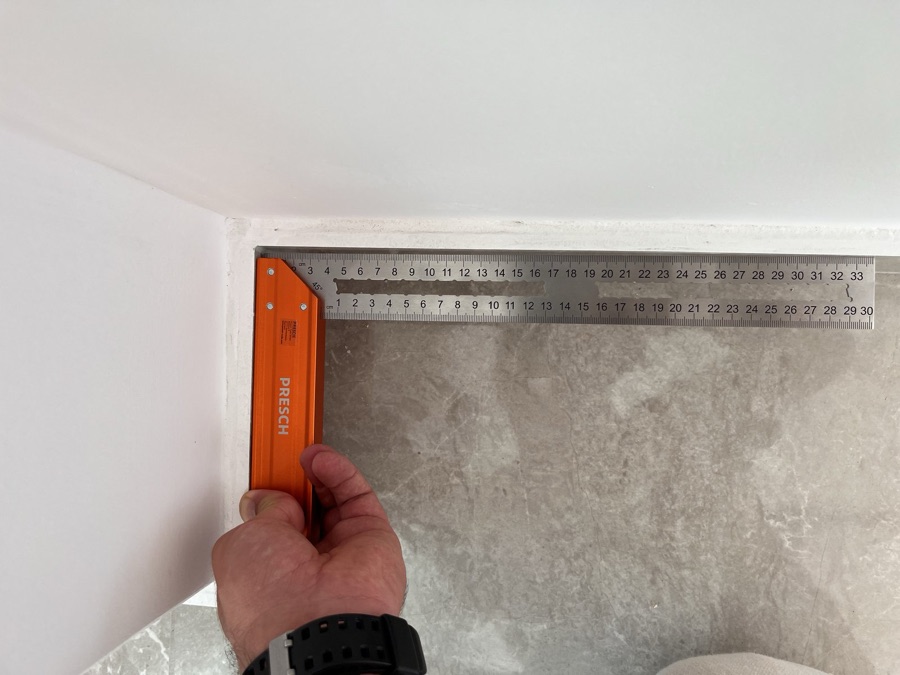 Carpenter's square held in a wall corner showing it is out of square